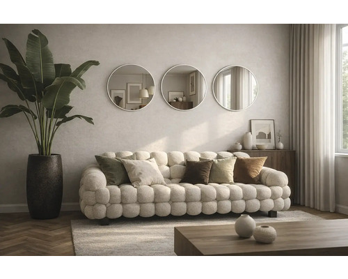 Vardagsrum med soffa, kuddar, runda speglar och krukväxt