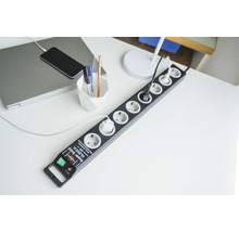 Grenuttag med överspänningsskydd på ett skrivbord med bärbar dator och telefon