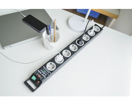 Grenuttag med överspänningsskydd på ett skrivbord med bärbar dator och telefon