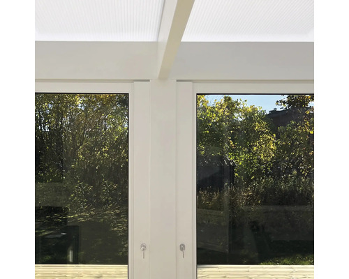 Modern vit terrassövertäckning med ljusgenomsläppligt tak, glasskjutväggar och utsikt mot trädgården.