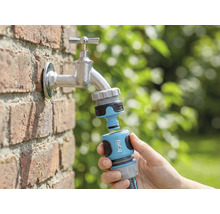 Trädgårdsscen med vattenkran, med for_q trädgårdsslangkoppling ansluten i handen