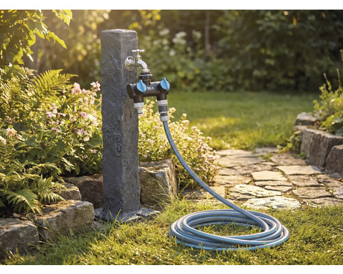 Trädgårdsscen med vattenkran, fördelare och trädgårdsslang på en gräsmatta