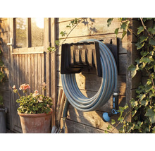 Trädgårdsscen med slangvinda, monterad på en trävägg med trädgårdsslang