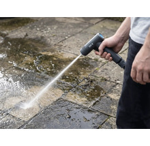 En person rengör stenplattor utomhus med en sladdlös högtryckstvätt.