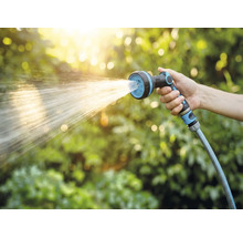 Hand som håller trädgårdsslang med sprutmunstycke vid vattning