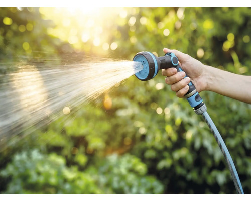 Hand som håller trädgårdsslang med sprutmunstycke vid vattning