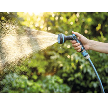 Hand håller trädgårdsslang med sprutmunstycke