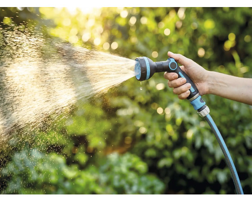 Hand håller trädgårdsslang med sprutmunstycke