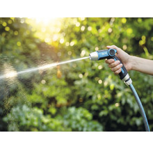 En hand håller en for_q trädgårdsspruta från vilken det kommer en vattenstråle.