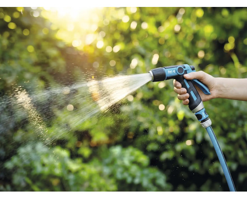 En person håller i en trädgårdsspruta och vattnar växter.