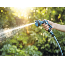 En hand håller i en trädgårdsspruta som sprutar vatten