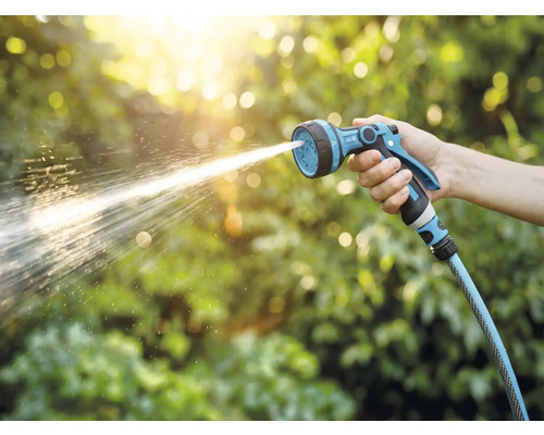 En hand håller i en trädgårdsspruta som sprutar vatten