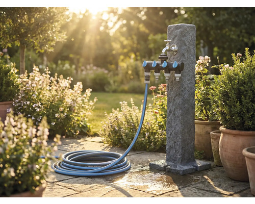 Trädgårdsscen med vattenpelare, multipel fördelare och trädgårdsslang på stenterass