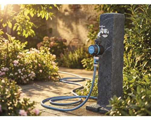 Trädgårdsscen med vattenkran, bevattningstimer och trädgårdsslang