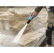 En person rengör en stenterass med en for_q trädgårdsslang
