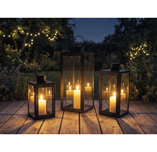 Tre lyktor med ljus på en träaltan i trädgården