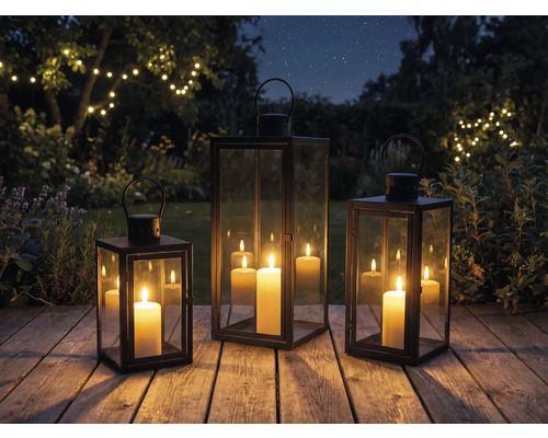 Tre lyktor med ljus på en träaltan i trädgården
