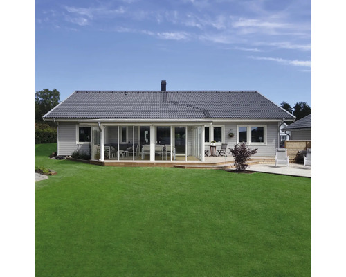 Modernt enplanshus med grå fasad, mörkt tegeltak, stor inglasad veranda och en välskött gräsmatta.