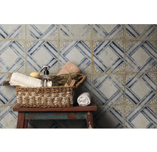 Dekorativ kakelvägg med geometriskt mönster och korg med badrumsartiklar på en pall