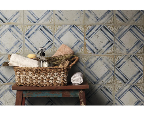 Dekorativ kakelvägg med geometriskt mönster och korg med badrumsartiklar på en pall