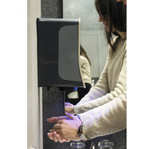 Kvinna använder en tvåldispenser i ett badrum.