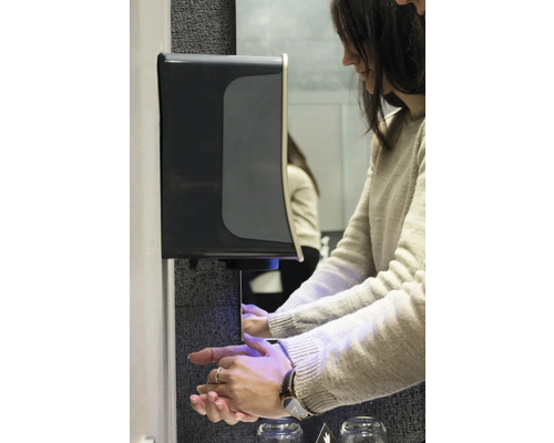 Kvinna använder en tvåldispenser i ett badrum.