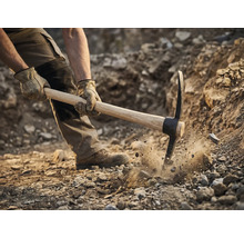 Man använder en hacka för att gräva i marken