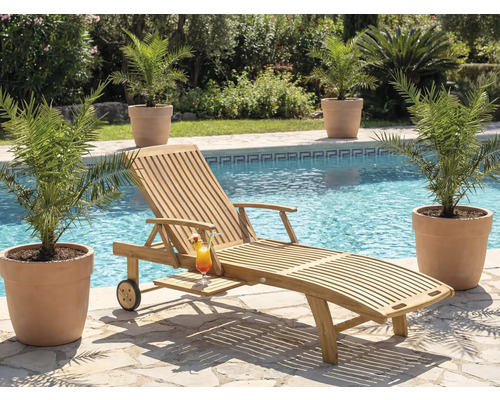 Scen med en solstol i trä, en cocktail och växter bredvid en pool.