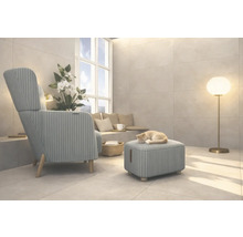 Vardagsrum med fåtölj, pall, golvlampa och en katt som sover på pallen