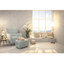 Ljust vardagsrum med fåtölj, fotpall och stort fönster