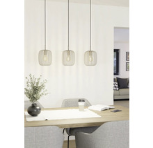 Tre metallpendellampor ovanför ett matbord med dekoration och stolar.