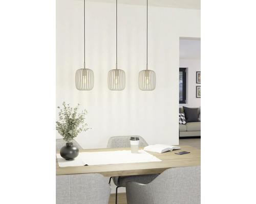 Tre metallpendellampor ovanför ett matbord med dekoration och stolar.