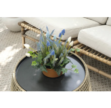 Dekorativa konstgjorda blommor i kruka på ett rottingbord