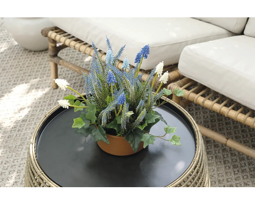 Dekorativa konstgjorda blommor i kruka på ett rottingbord