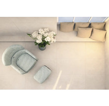 Ljust rum med fåtölj, fotpall, blomsterarrangemang och soffa med kuddar, uppifrån