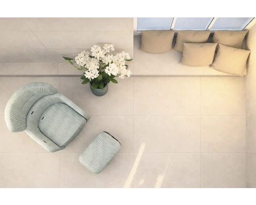 Ljust rum med fåtölj, fotpall, blomsterarrangemang och soffa med kuddar, uppifrån