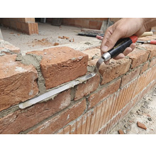 Hantverkare bearbetar tegelvägg med fogspackel