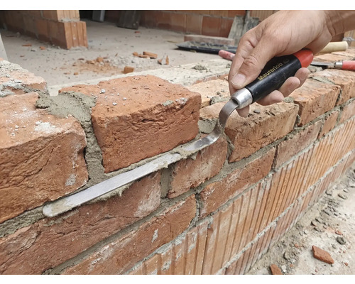 Hantverkare bearbetar tegelvägg med fogspackel