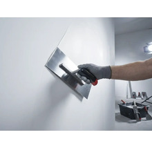 Hand med putsglättare som jämnar ut en vägg