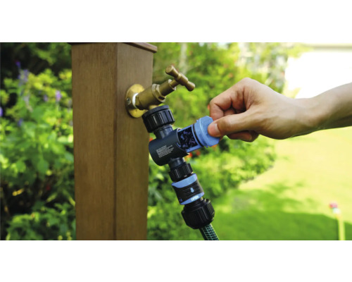 Trädgårdskran med vattenfördelare och ansluten trädgårdsslang i användning.