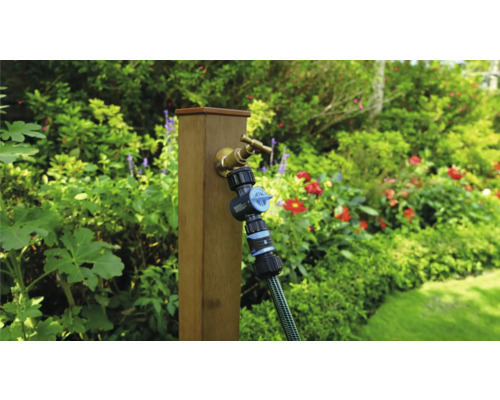 Trädgårdsscen med vattenkran, fördelare och slang på en trästolpe