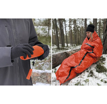 Person insvept i en orange räddningsfilt i skogen. Närbild av en förpackad räddningsfilt.
