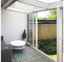 Modern terrasinglasning med vita skjutdörrar, trädäck, soffa och ljust glastak.