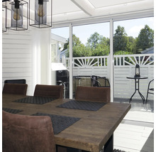 Ljus matplats med träbord, stolar i läderlook och skjutdörrar i glas mot en terrass med vitt staket.