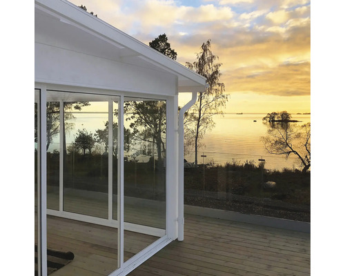 Inglasad veranda med utsikt över sjön i solnedgången.