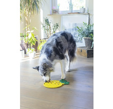En hund äter mat från en gul interaktiv matleksak i form av en ananas.
