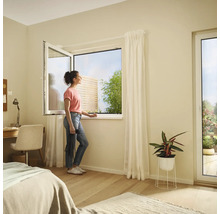 Ljust sovrum med ett fönster som kan öppnas och en kvinna som tittar ut