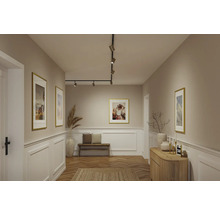 Modern hall med svart skensystem och spotlights, bröstpanel, träbänk och fiskbensparkett.