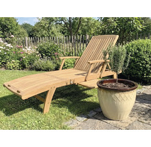 Trädgårdsliggstol i trä bredvid en kruka med växt i trädgården