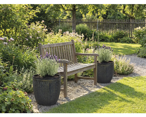 Trädgårdslandskap med träbänk och växter i strukturerade planteringskärl